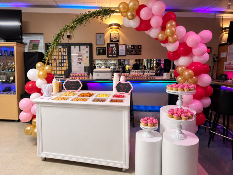 Chuchulucos dessert bar with a pink and gold balloon arch