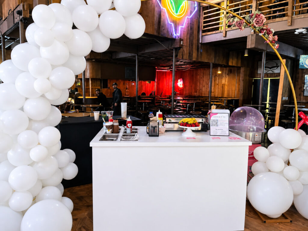 Chuchulucos dessert cart with a white balloon arch at a Denver event